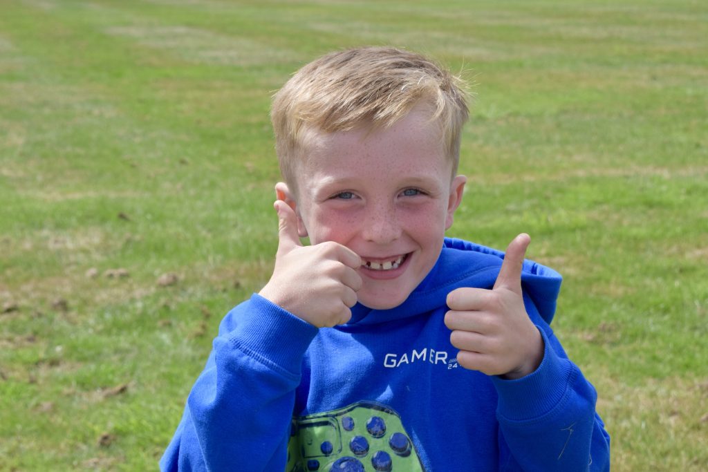 A young person supported by Active Fusion, smiling and giving a thumbs up